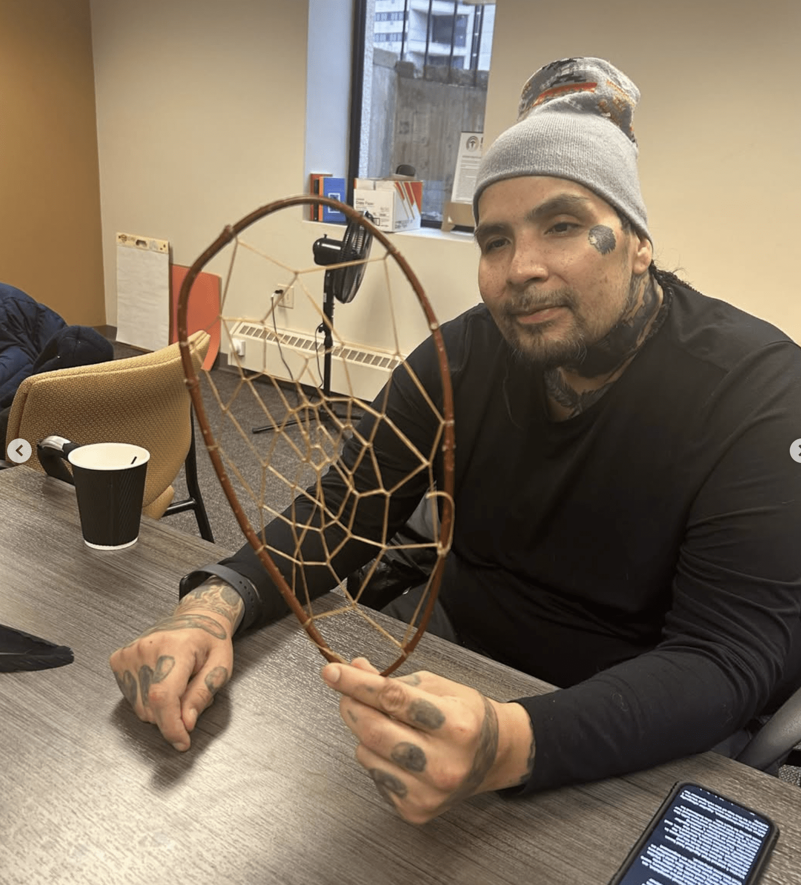 a person sitting at a table holding a dream catcher