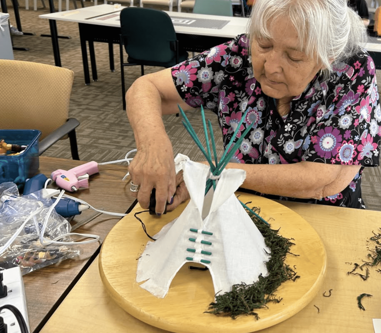 an older person working on a model of a teepee