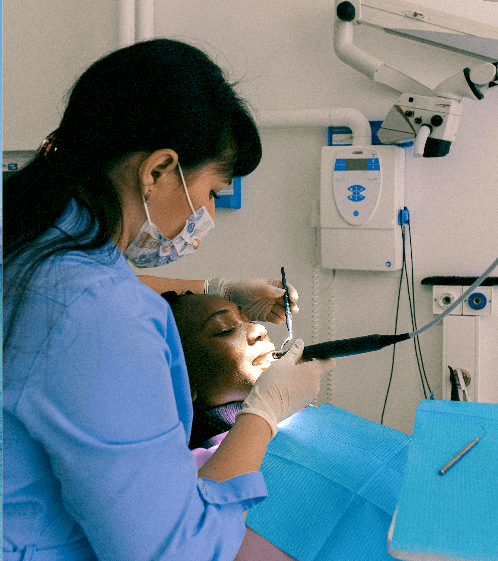 a person in a blue shirt and mask working on a patient